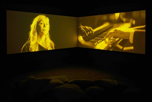 Gabrielle Goliath, ‘This song is for…’, 2019. Installation vidéo 4K couleur, son, 11 doubles projections synchronisées, texte vinyle. 201 min 36 sec (11 chansons). Collection Mudam Luxembourg. Donation 2024 – A&O Shearman. Vue de l’exposition ‘I’ve grown roses in this garden of mine’, 03.10-31.10.2019, Goodman Gallery, Londres © Goodman Gallery, Londres