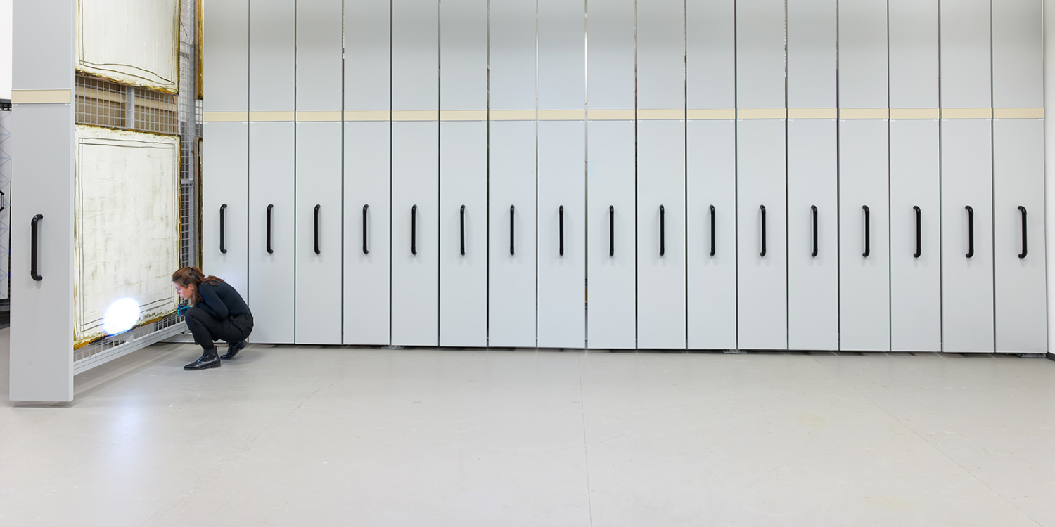 A person inspecting a painting in the Mudam Collection stock.